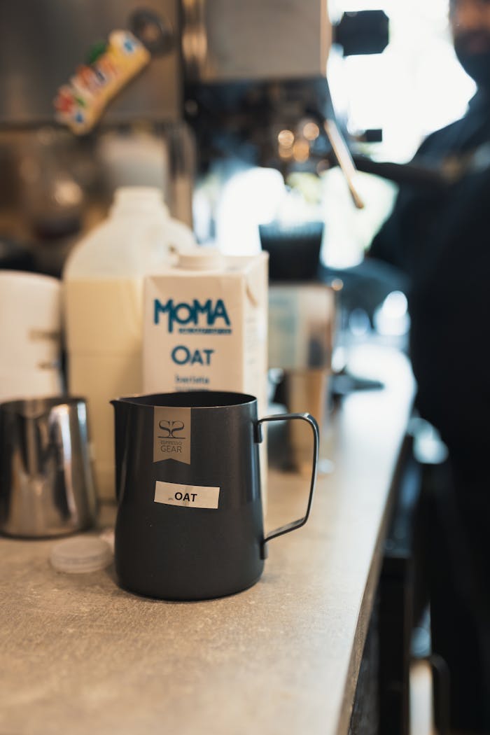 A barista prepares coffee using oat milk in a cozy cafe setting.